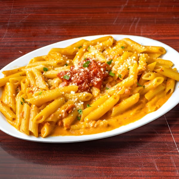 Penne pasta in a creamy orange sauce, topped with red marinara, parmesan cheese, and parsley.