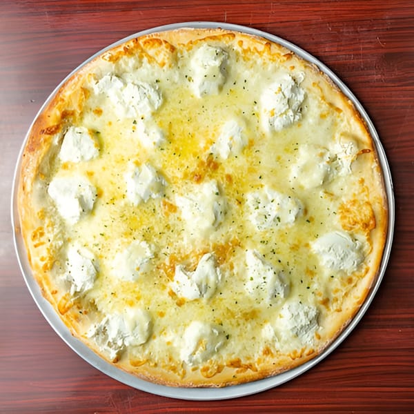 Big Joe's Pizzeria white pizza with ricotta cheese dollops and herbs on a wooden table.