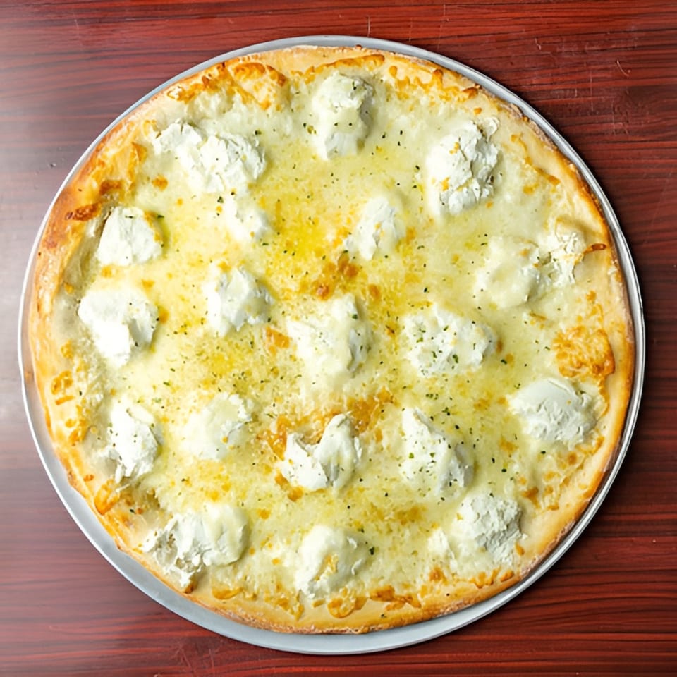 Big Joe's Pizzeria white pizza with ricotta cheese dollops and herbs on a wooden table.
